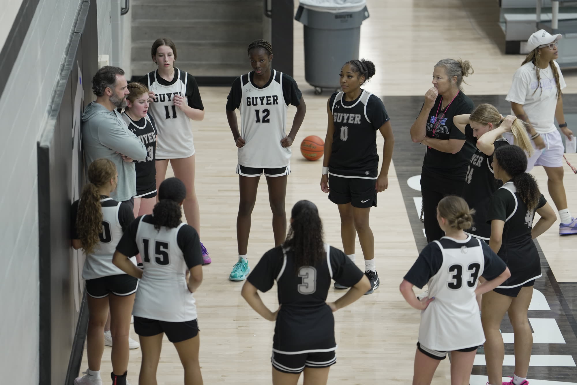 Overhead view of the Denton Guyer team gathered with Coach Floyd and staff in the gym