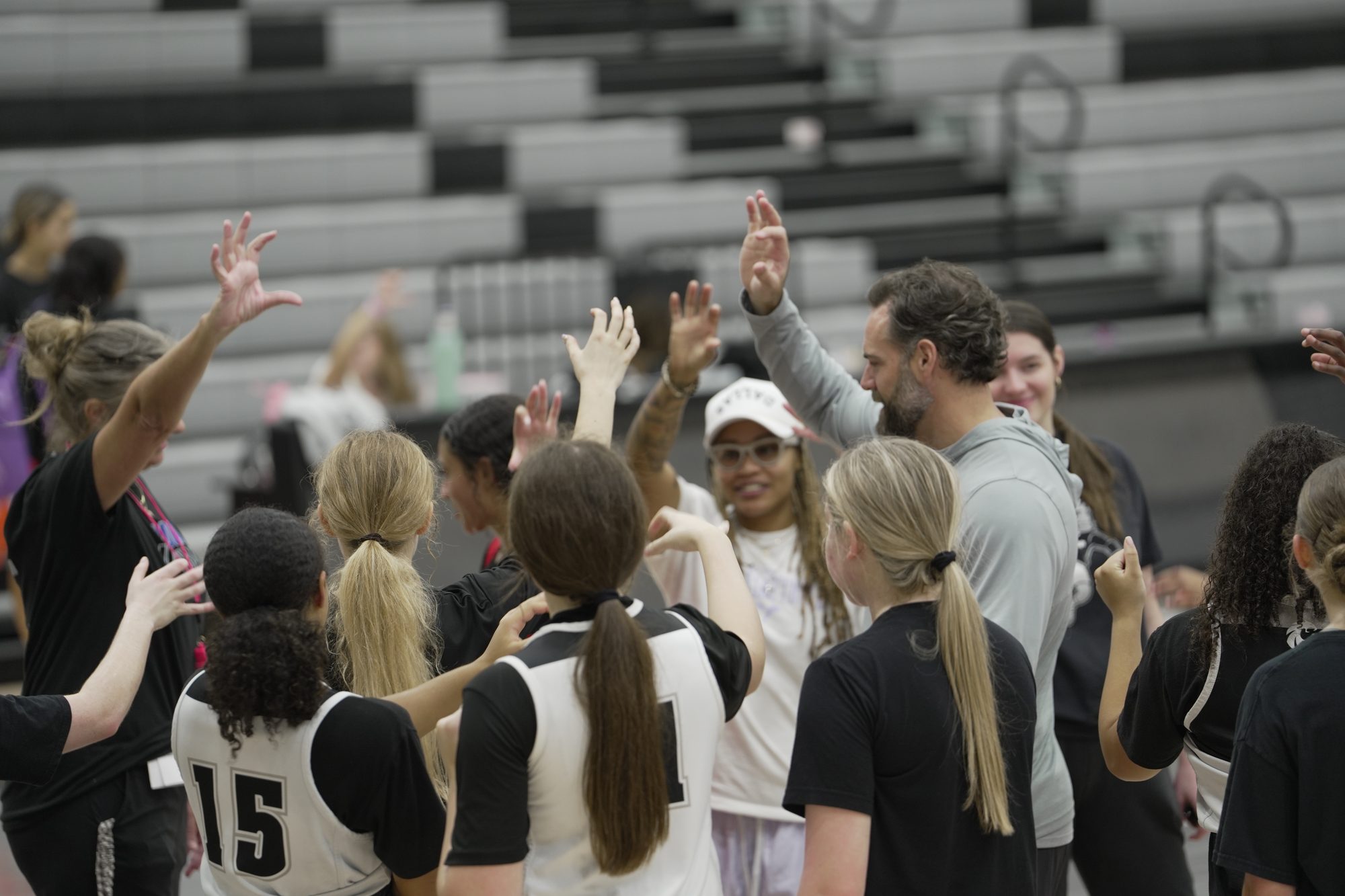 Guyer players and coaches throw up the Wildcat hand sign together in the gym.