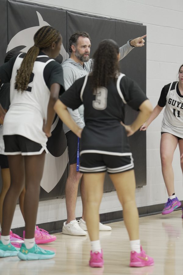Coach Floyd points to the next spot while players listen with hands on hips.